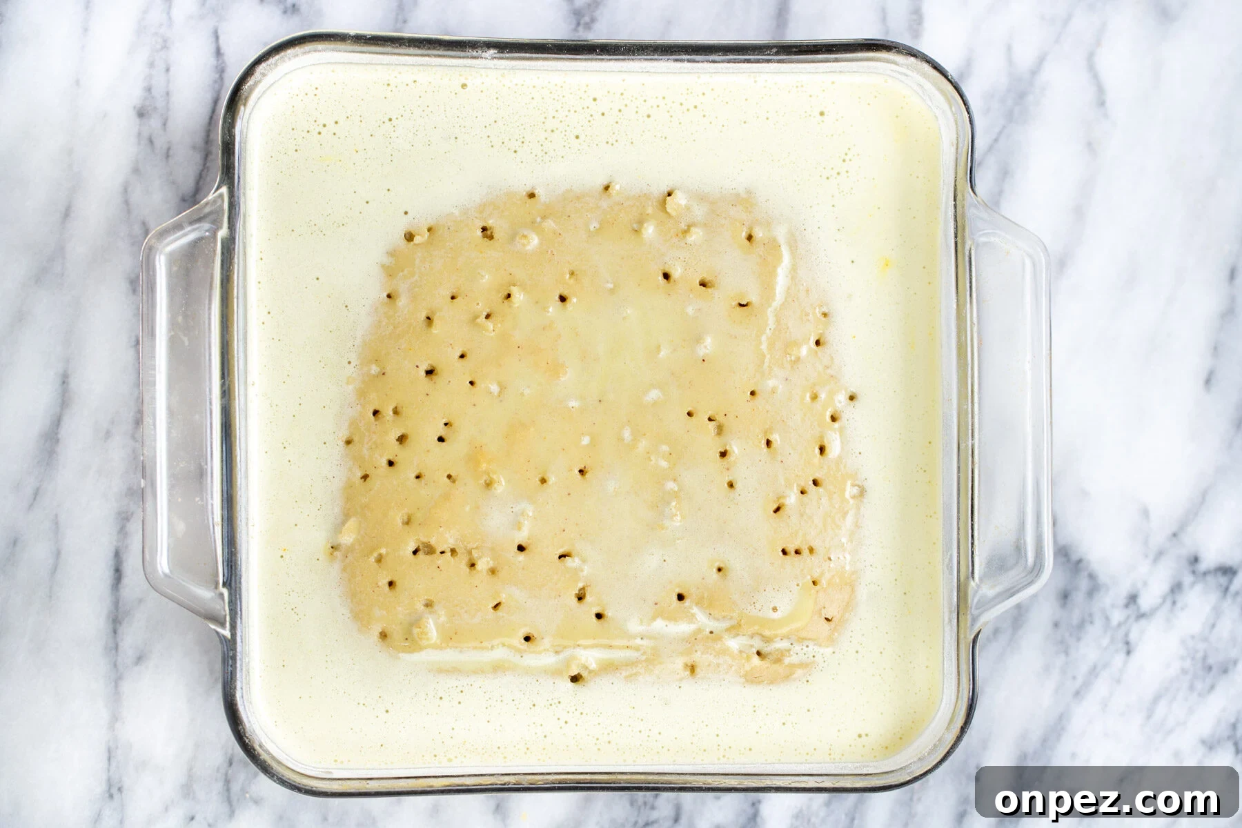 nut milk being poured over sponge cake to make vegan tres leches