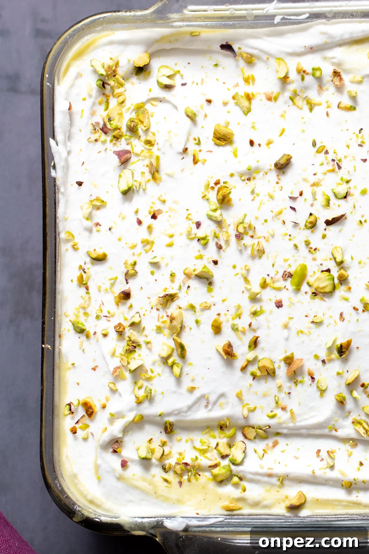 overhead shot of vegan ras malai tres leches cake sprinkled with pistachios
