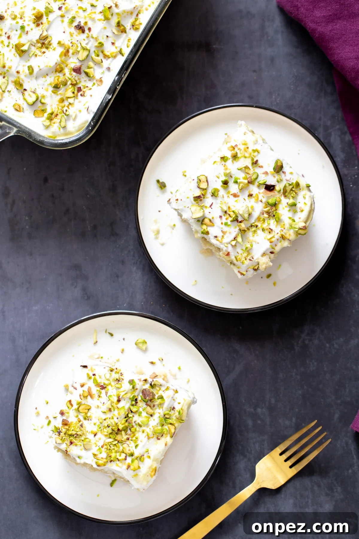 overhead shot of two slices of vegan tres leches sprinkled with pistachios