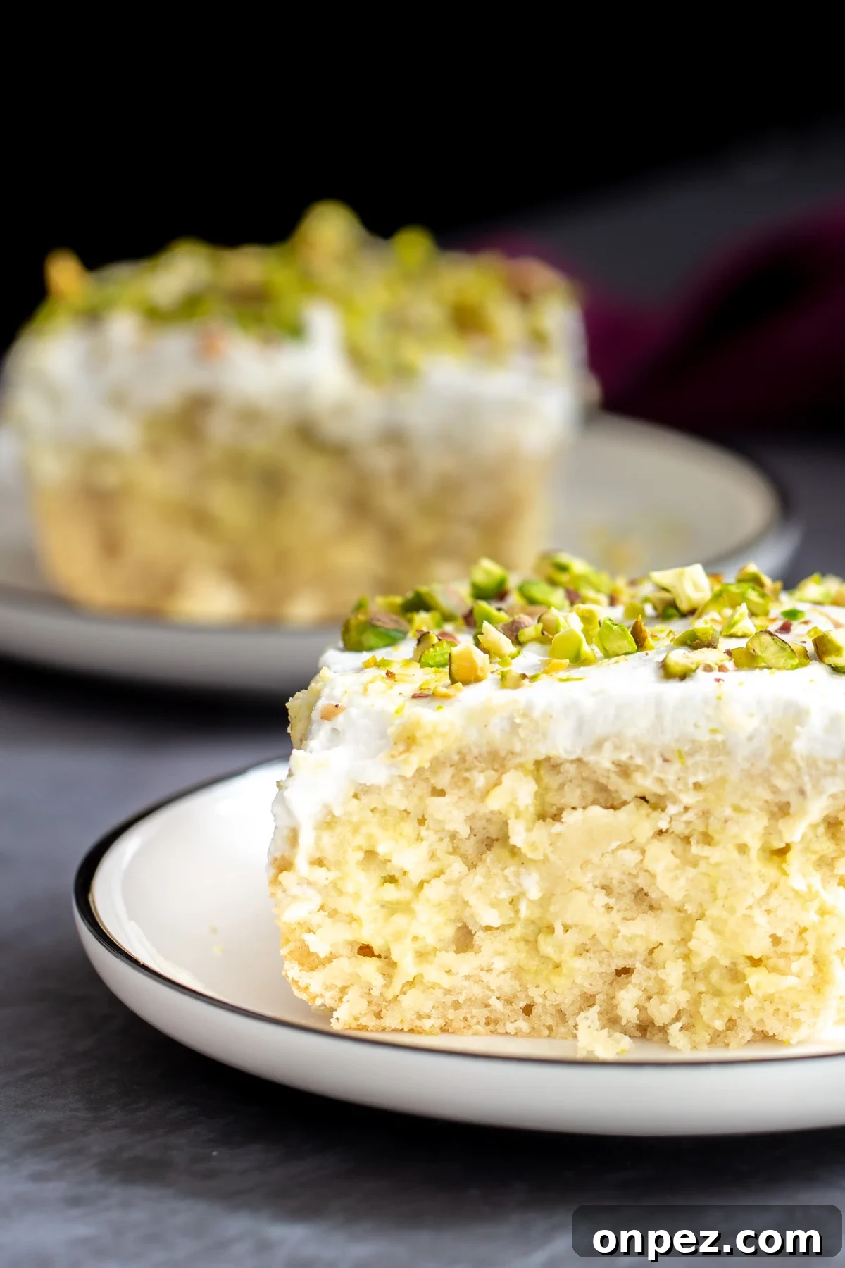 side view of a slice of vegan tres leches cake sprinkled with pistachios