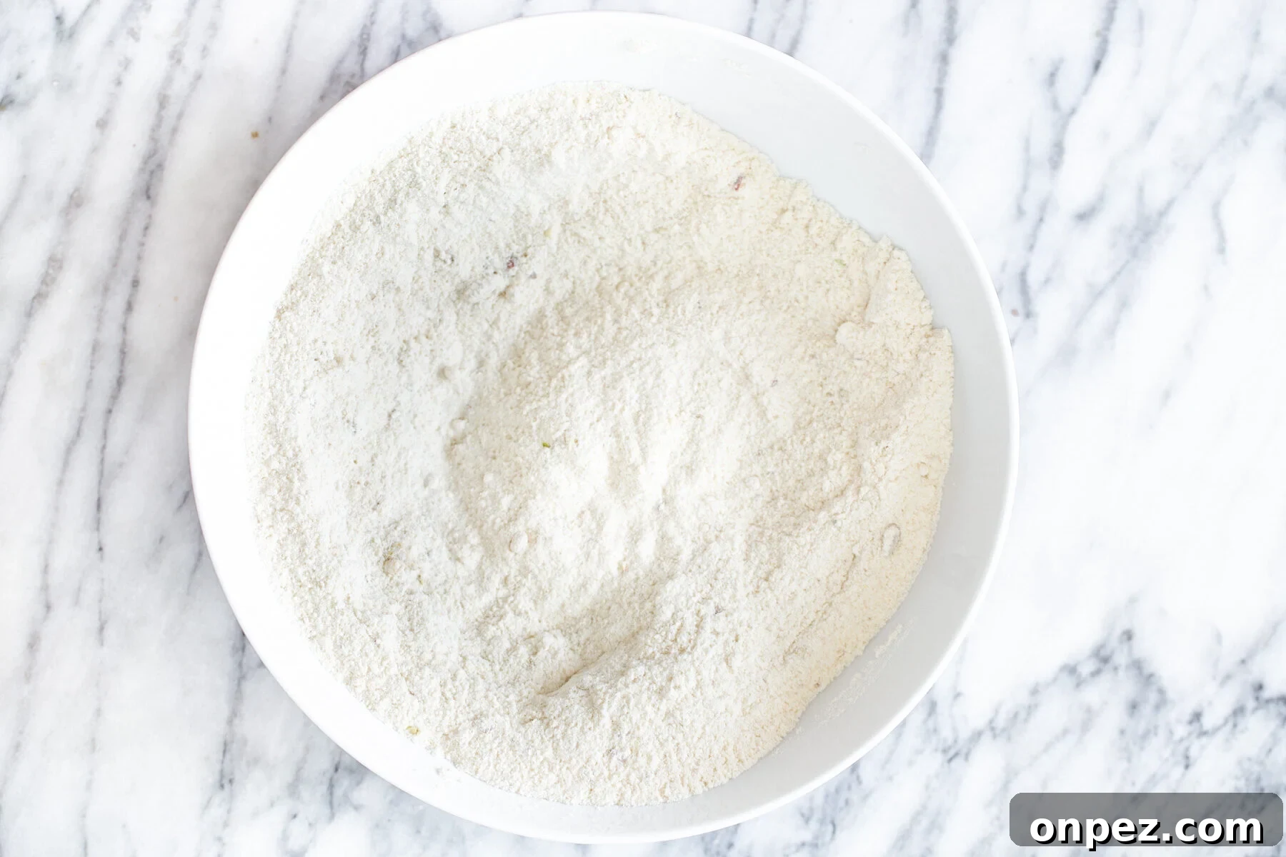 dry ingredients for vegan tres leches cake in a white bowl