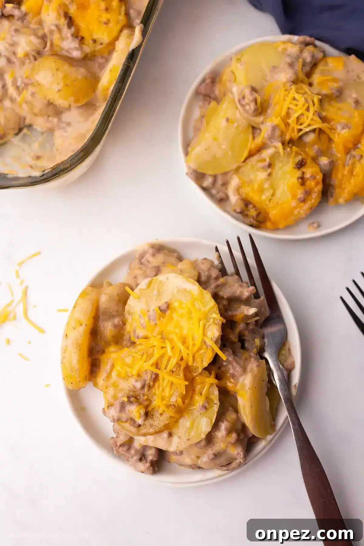 Two servings of hamburger potato casserole on white plates.
