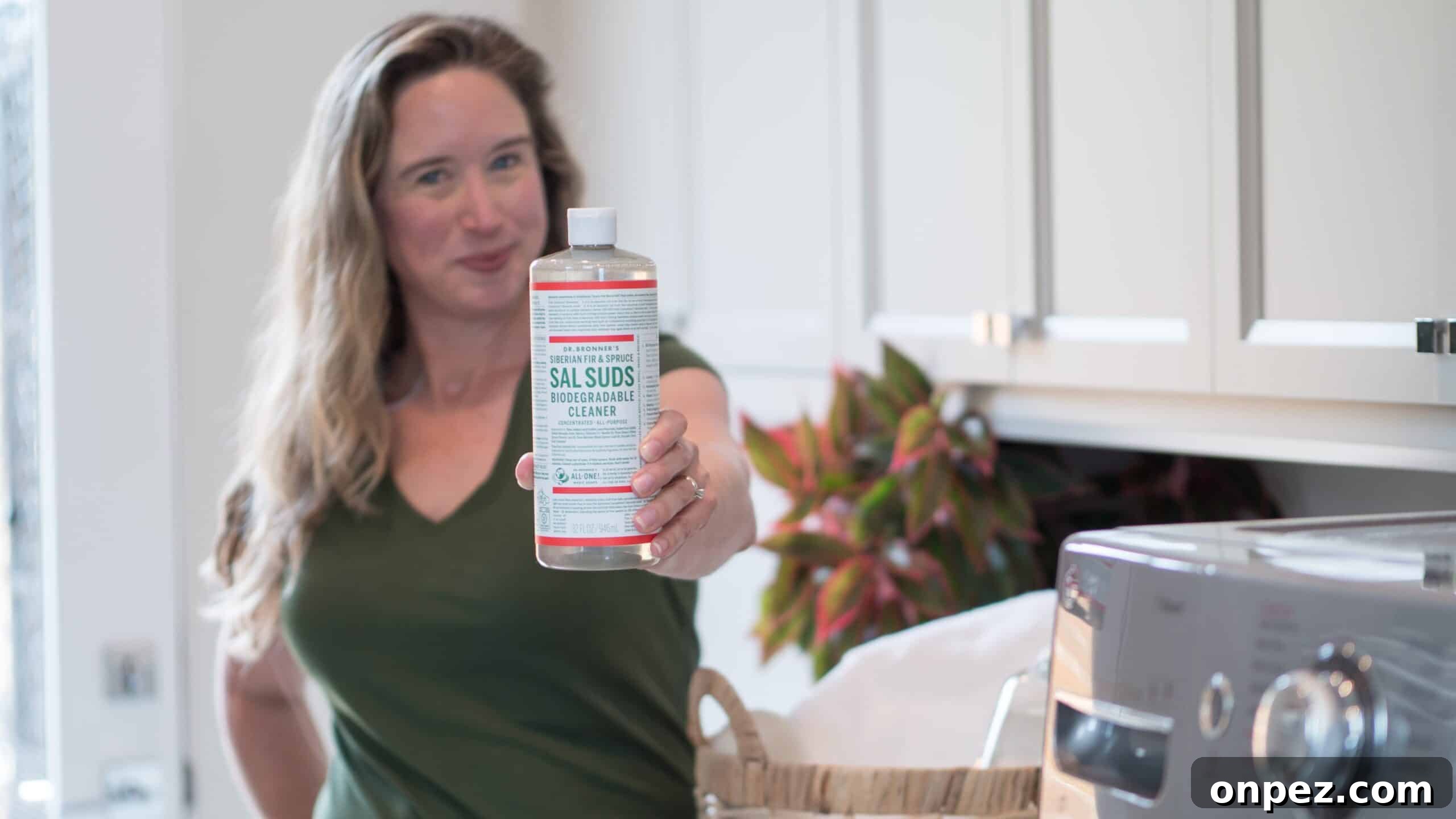 Sustainable Laundry Tips with Dr. Bronner’s 2 Lisa Bronner holding out a bottle of Sal Suds in her laundry room.