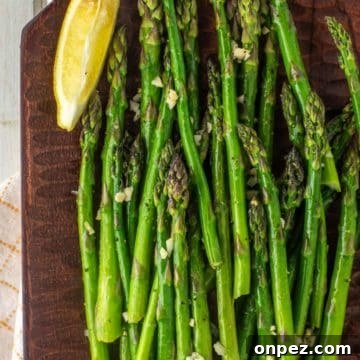 overhead shot of smoked asparagus on wood board with slice of lemon