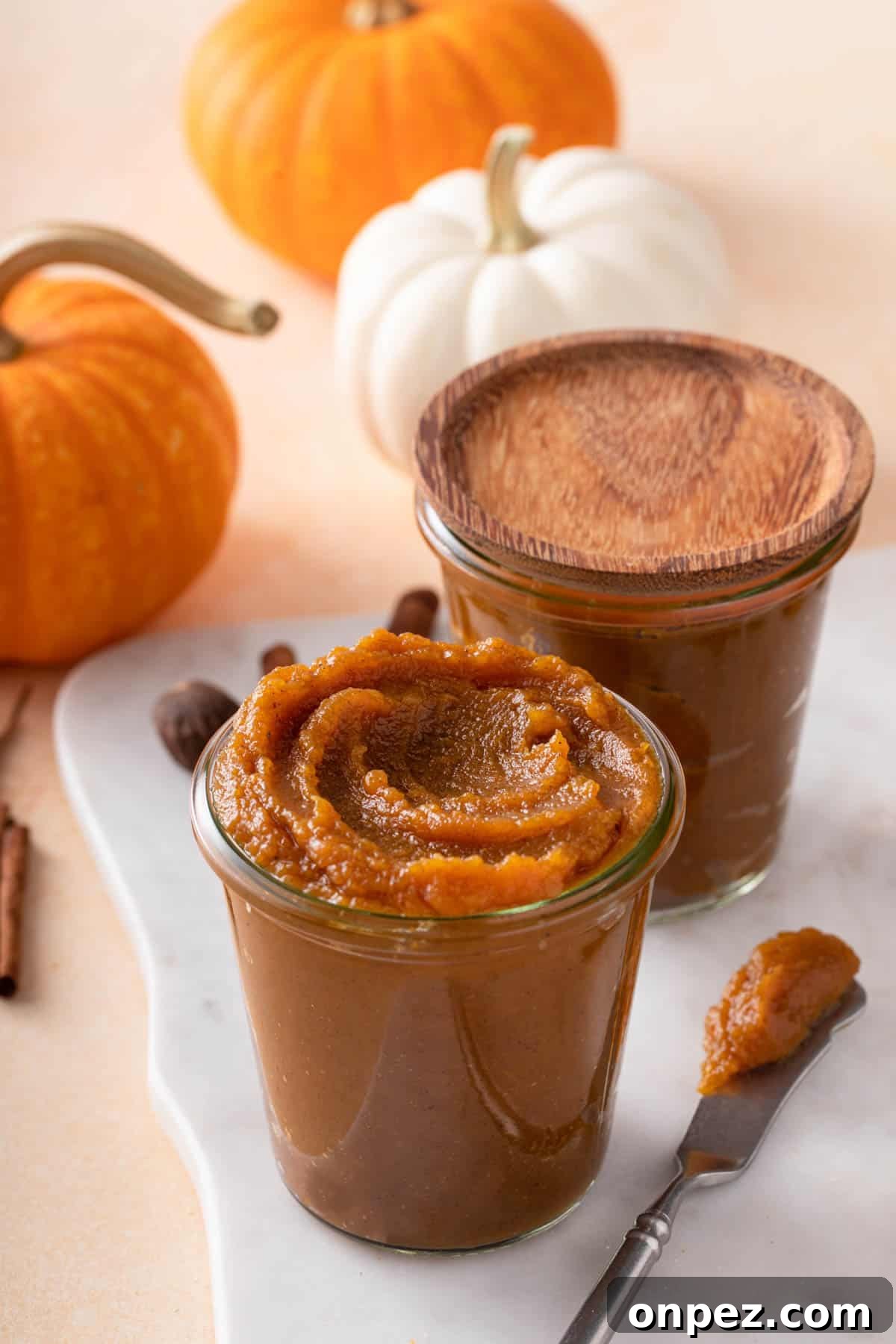 a butter knife or spreader with pumpkin butter on it lies next to a jar