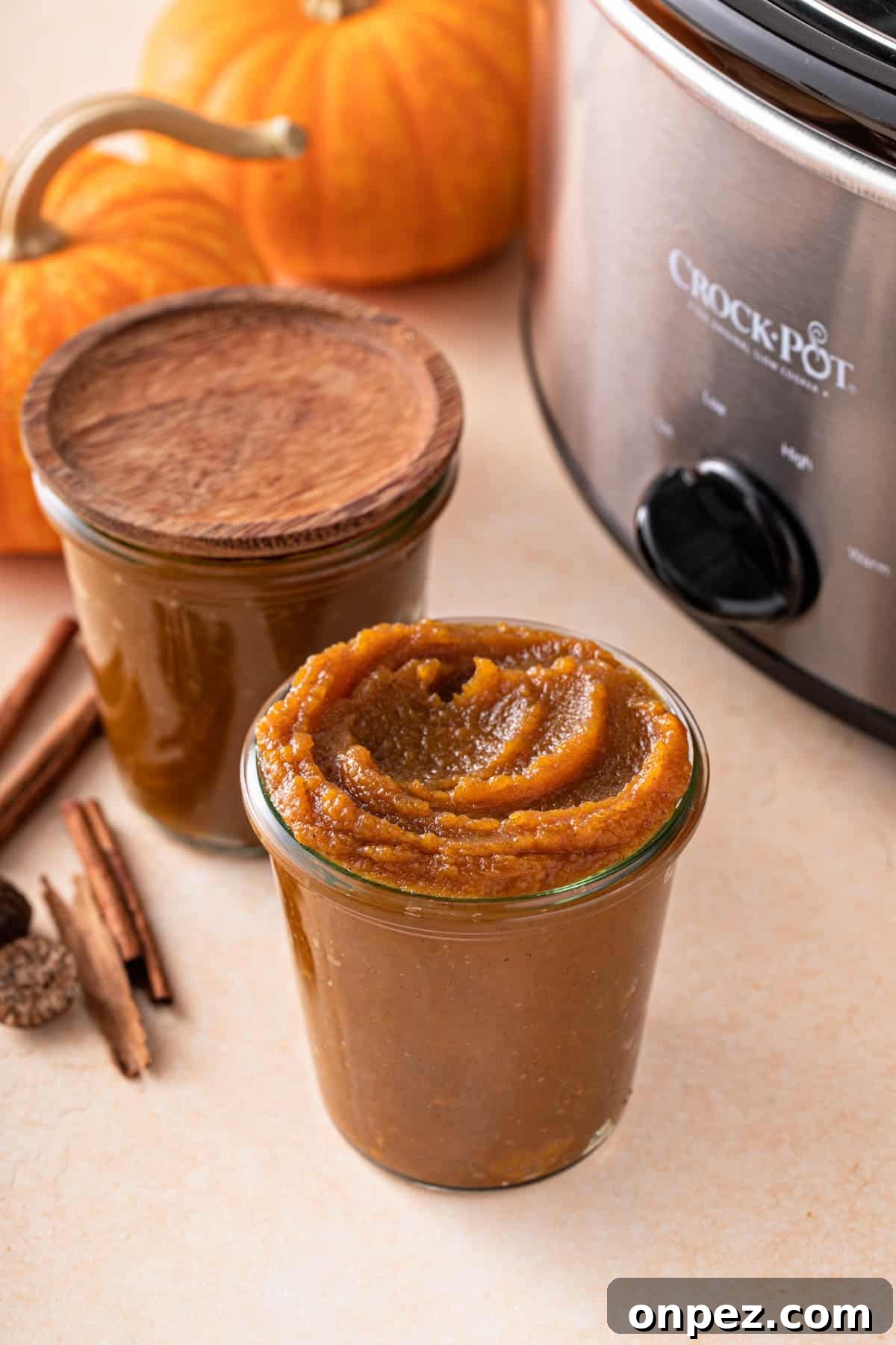 a slow cooker next to two jars of pumpkin butter