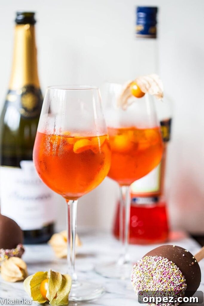 Two aperol spritz's with bottles in the background