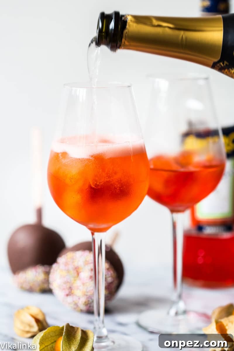 Bottle of sparking wine pouring into a glass with orange drink