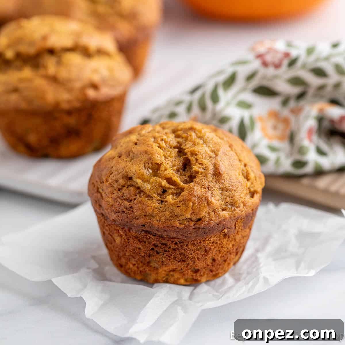Pumpkin Banana Muffins Recipe with Warm Fall Spices 2 A pumpkin banana muffin on a piece of parchment paper.