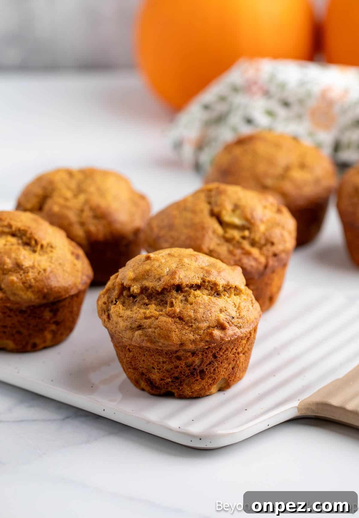 Pumpkin Banana Muffins Recipe with Warm Fall Spices 6 Banana Pumpkin Muffins on a white board.