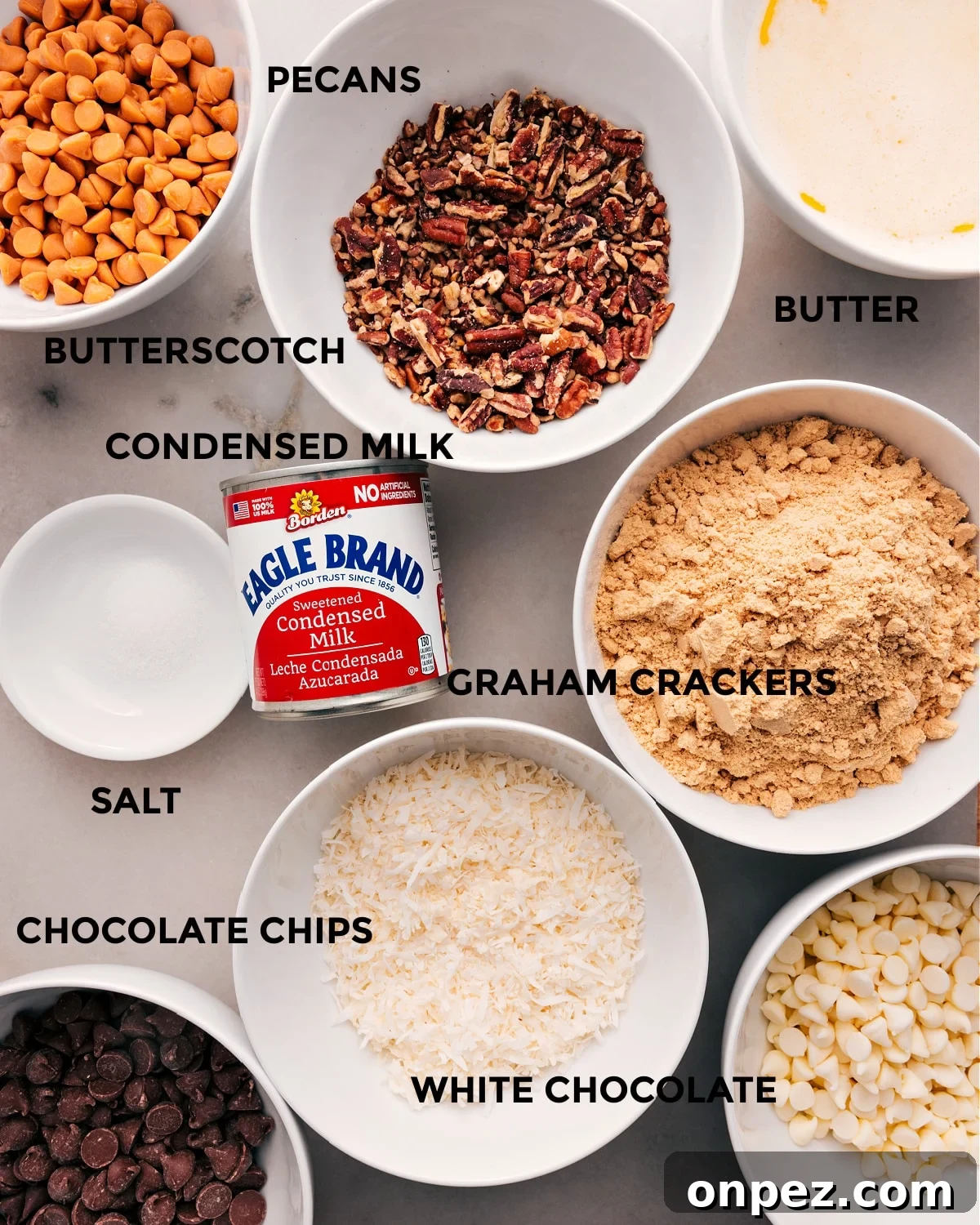 All the ingredients prepped for easy assembly—butter, butterscotch, pecans, condensed milk, graham crackers, salt, coconut, and chocolate chips.