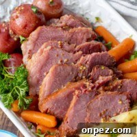 Brown Sugar Corned Beef and Cabbage with Apple Juice 6 sliced corned beef with cabbage, potatoes, and carrots on a white platter