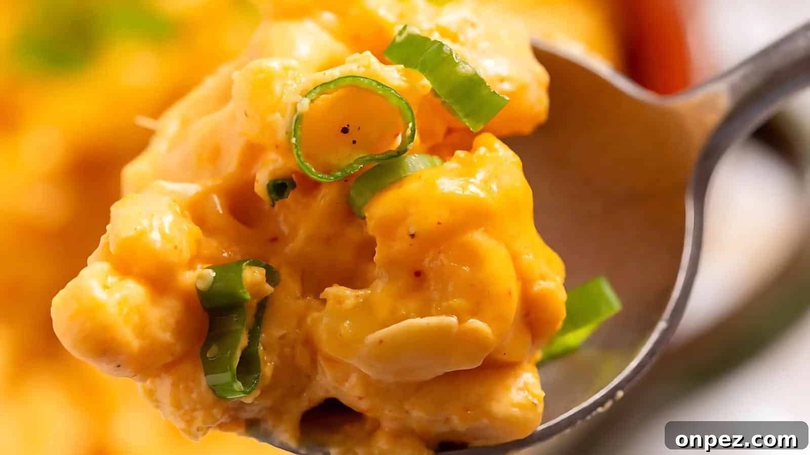 Close-up of a spoonful of creamy macaroni and cheese topped with chopped green onions.