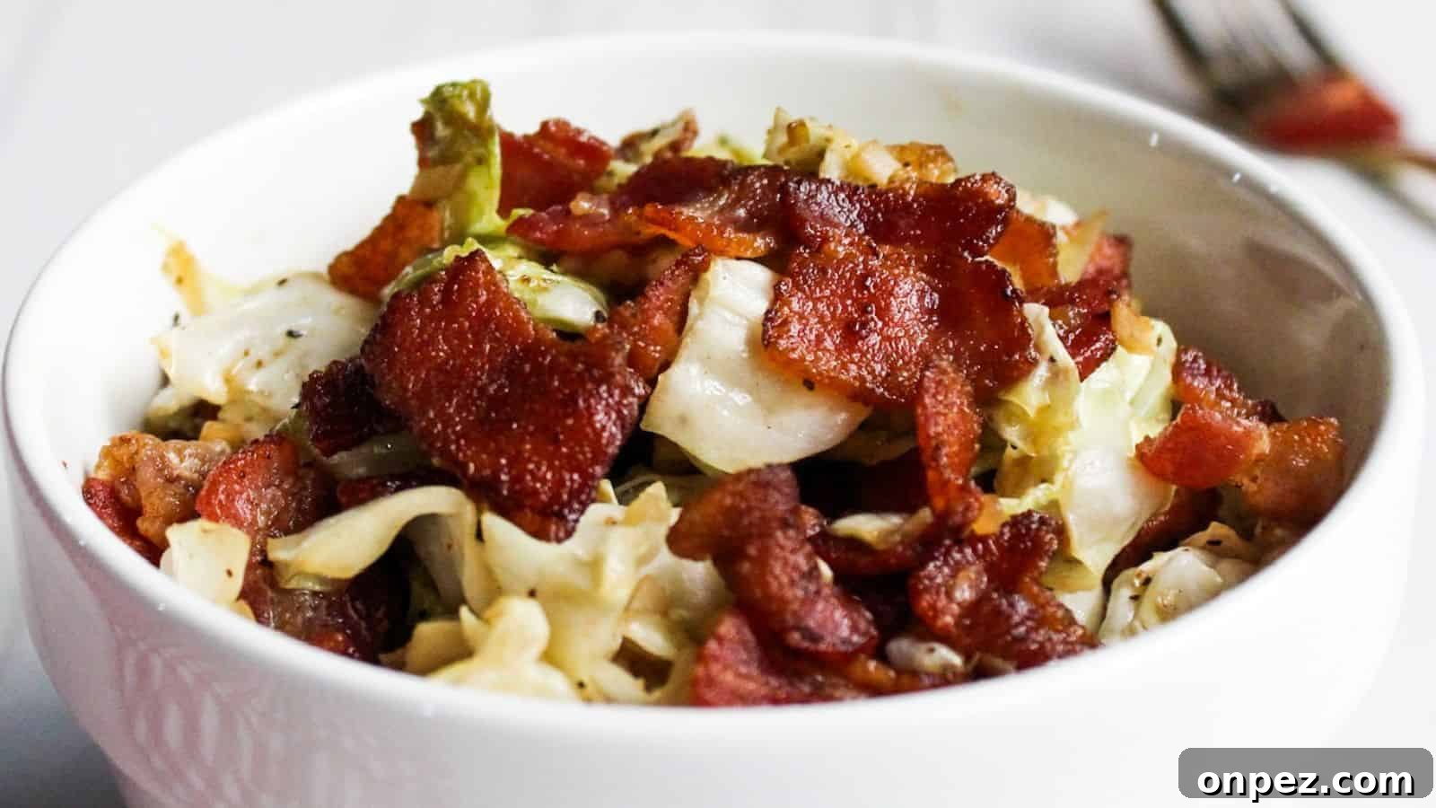 Cabbage and bacon in white serving bowl.