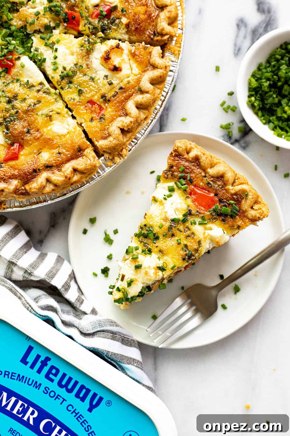 Quick Breakfast Quiche Recipe 12 A slice of quiche on a small plate next to the pan of quiche.