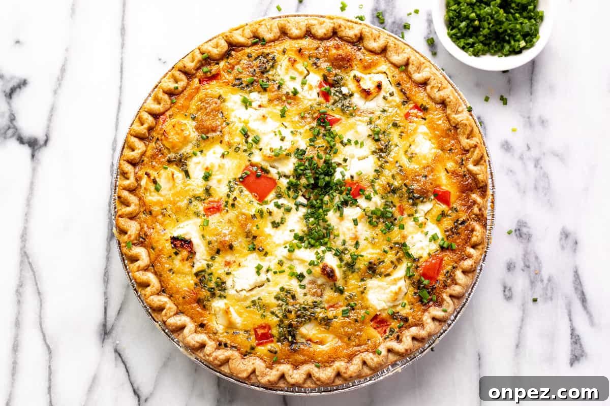 Quick Breakfast Quiche Recipe 10 Overhead shot of a quiche with red peppers and potatoes garnished with sliced chives.