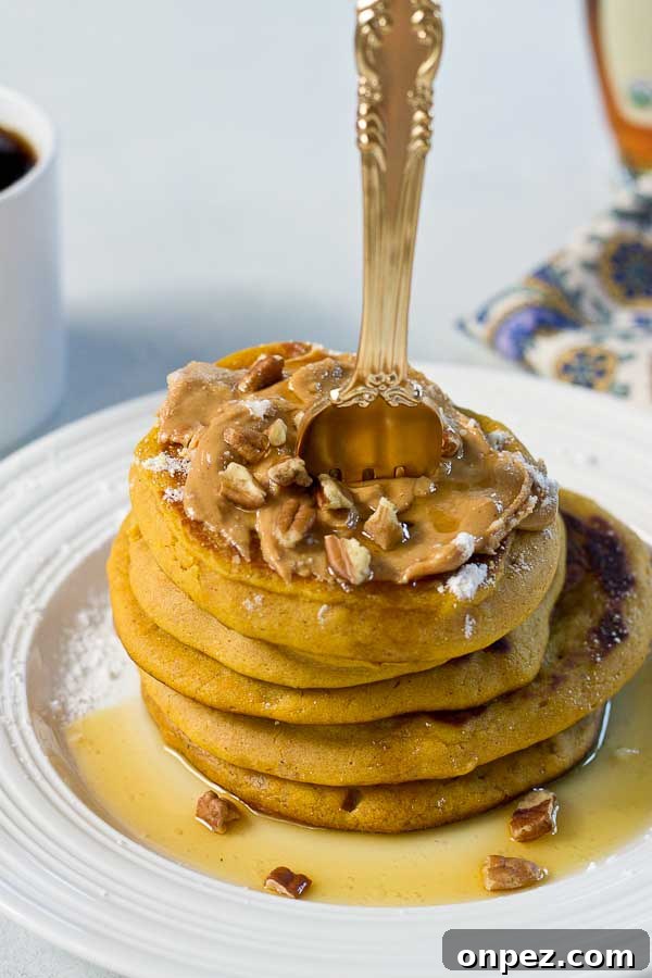 Peanut Butter Pumpkin Pancakes stacked with peanut butter and maple syrup.