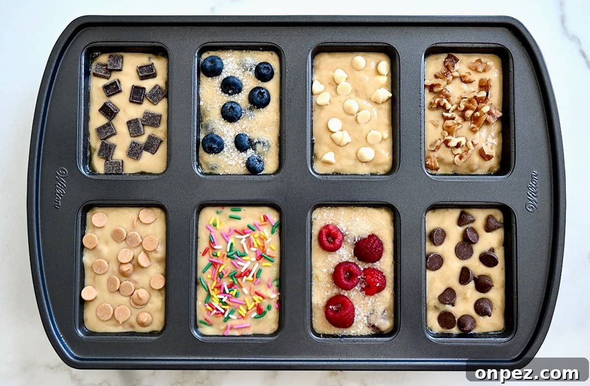 A top-down view of a mini loaf pan containing batter topped with a variety of toppings