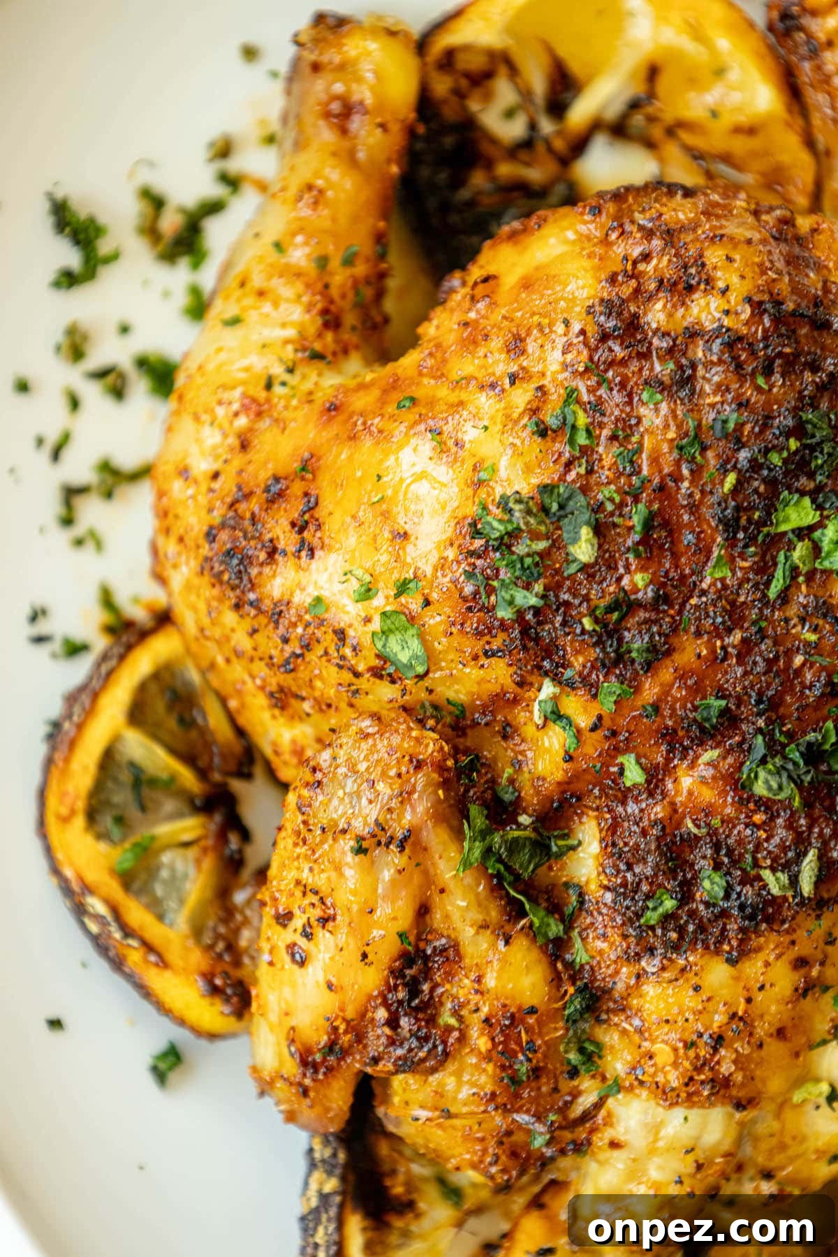 Crispy Air Fryer Cornish Hens Recipe with Herb Butter 2 air fried cornish game hens seasoned with herbs and topped with chopped parsley on a white plate