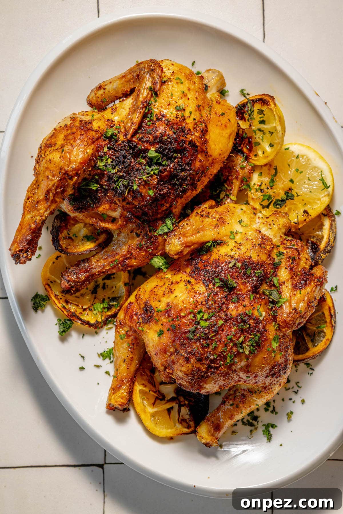 Crispy Air Fryer Cornish Hens Recipe with Herb Butter 11 air fried cornish game hens seasoned with herbs and topped with chopped parsley on a white plate