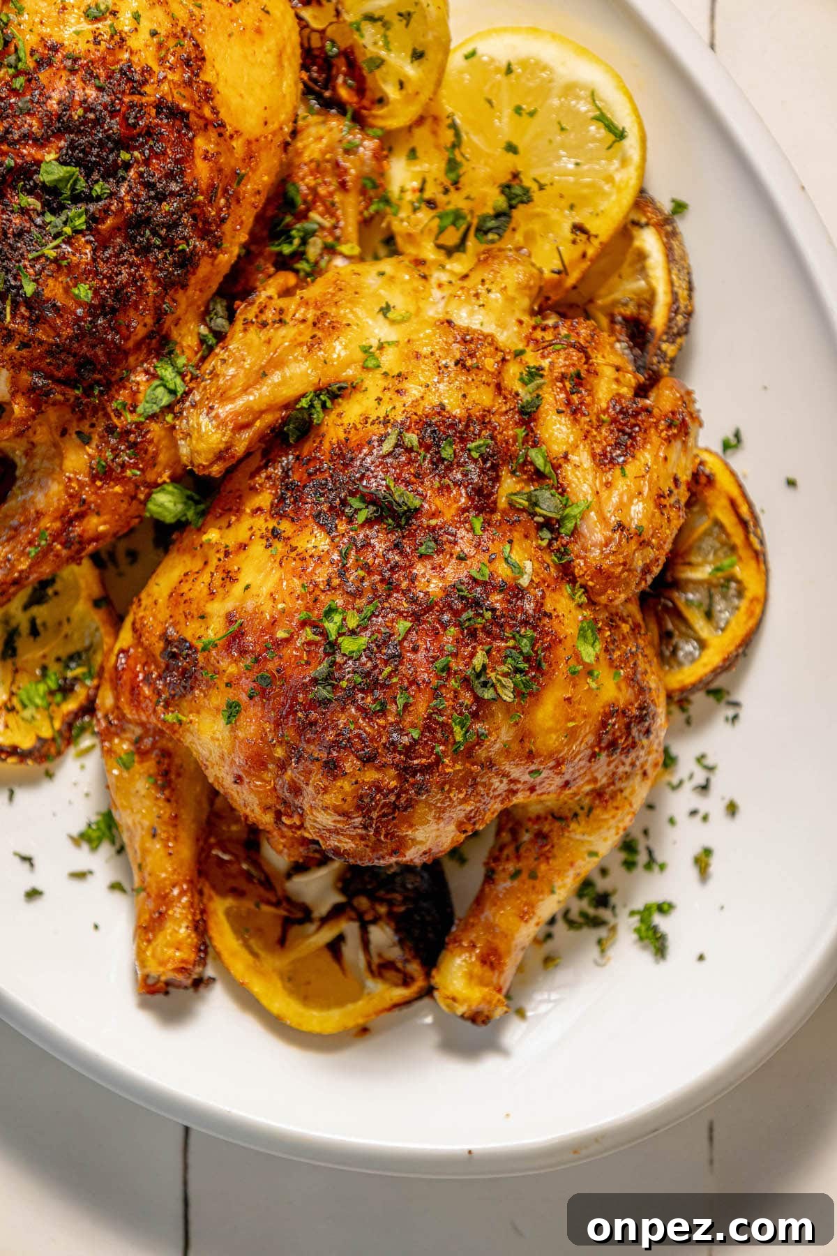 Crispy Air Fryer Cornish Hens Recipe with Herb Butter 12 air fried cornish game hens seasoned with herbs and topped with chopped parsley on a white plate