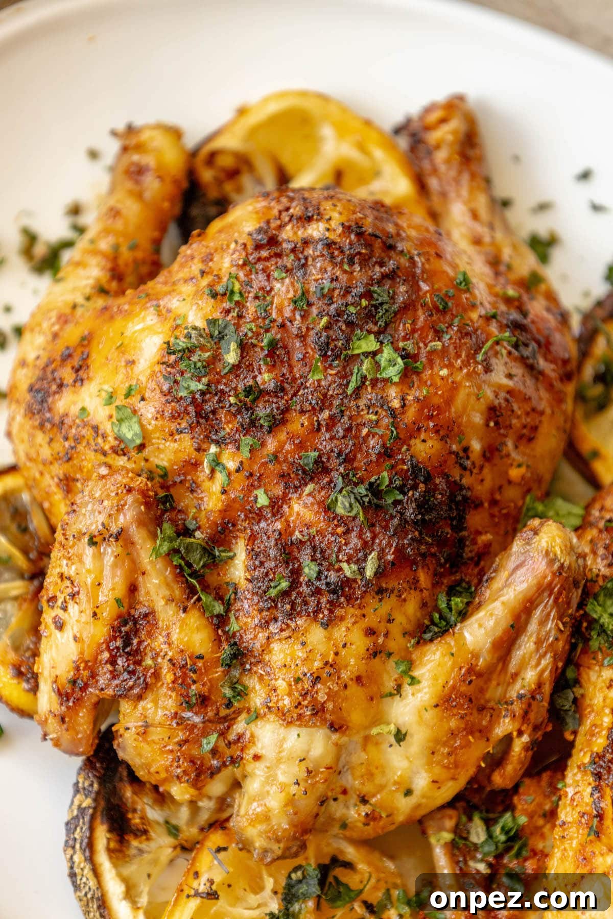 Crispy Air Fryer Cornish Hens Recipe with Herb Butter 4 air fried cornish game hens seasoned with herbs and topped with chopped parsley on a white plate
