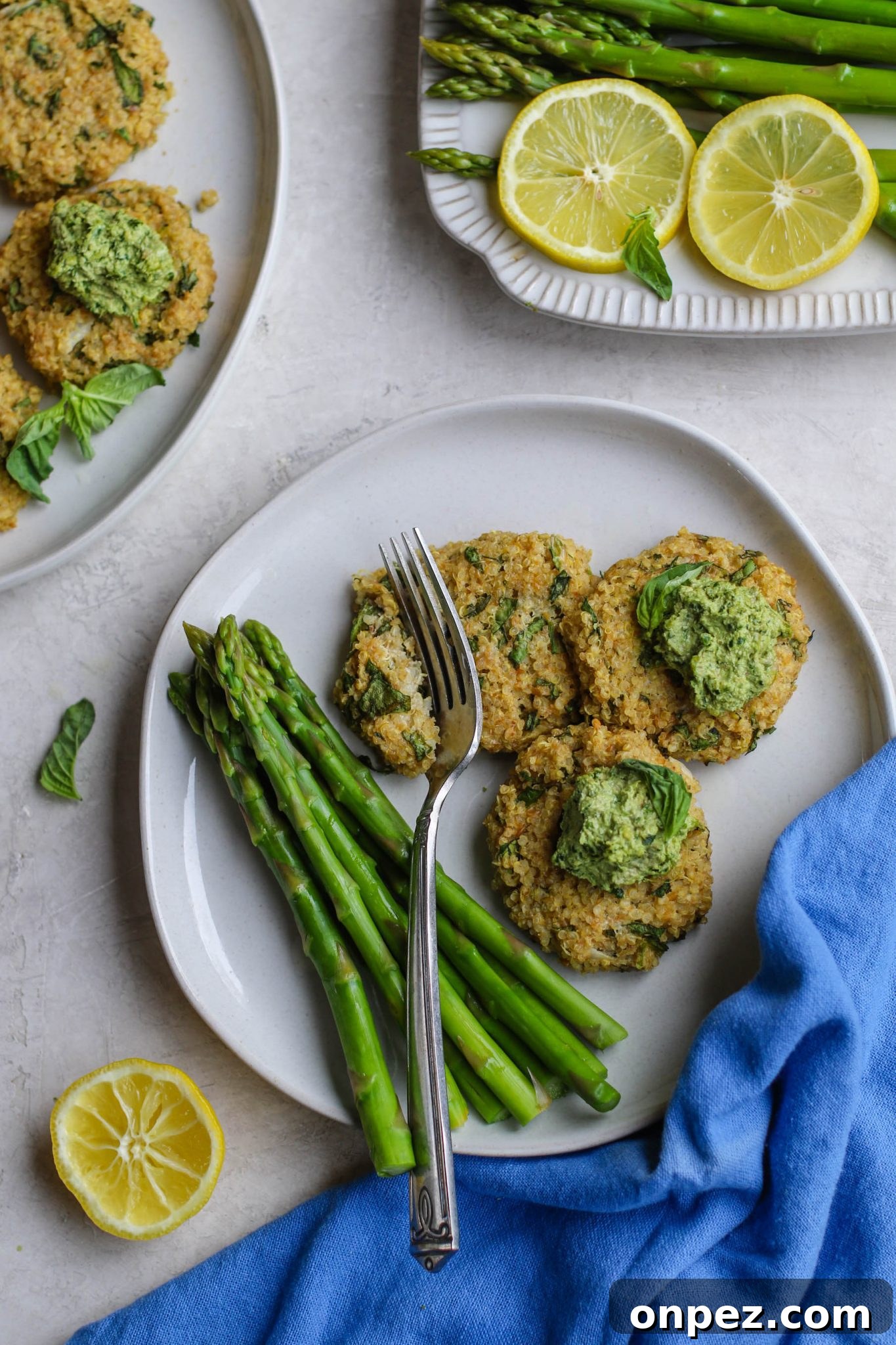 Quinoa Cakes with Basil Pesto served on plate with asparagus and fork cutting one by Flora & Vino