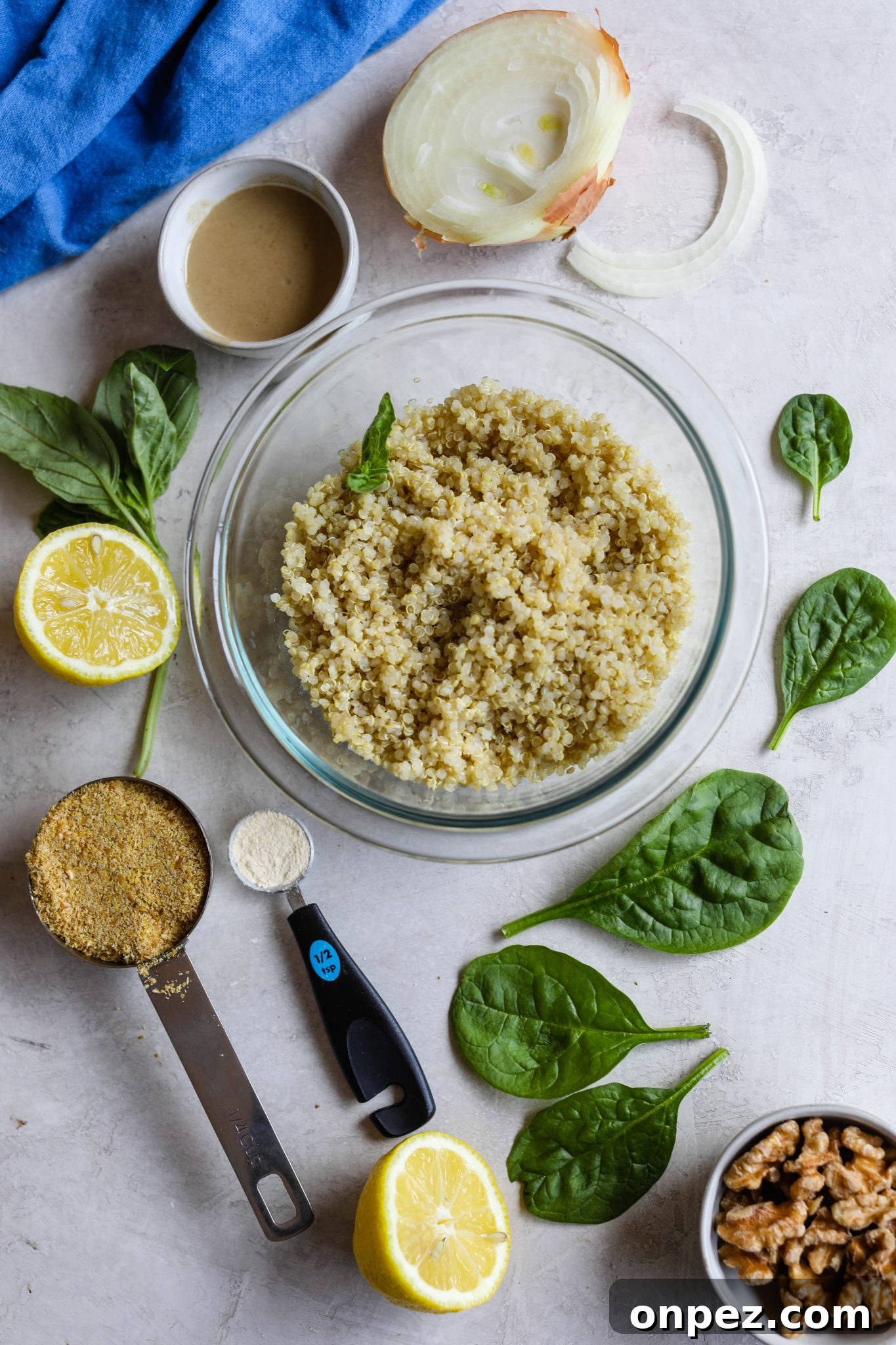 cooked quinoa in a bowl surrounded by spinach leaves, sliced onion, lemon, flaxseed, and walnuts by Flora & Vino