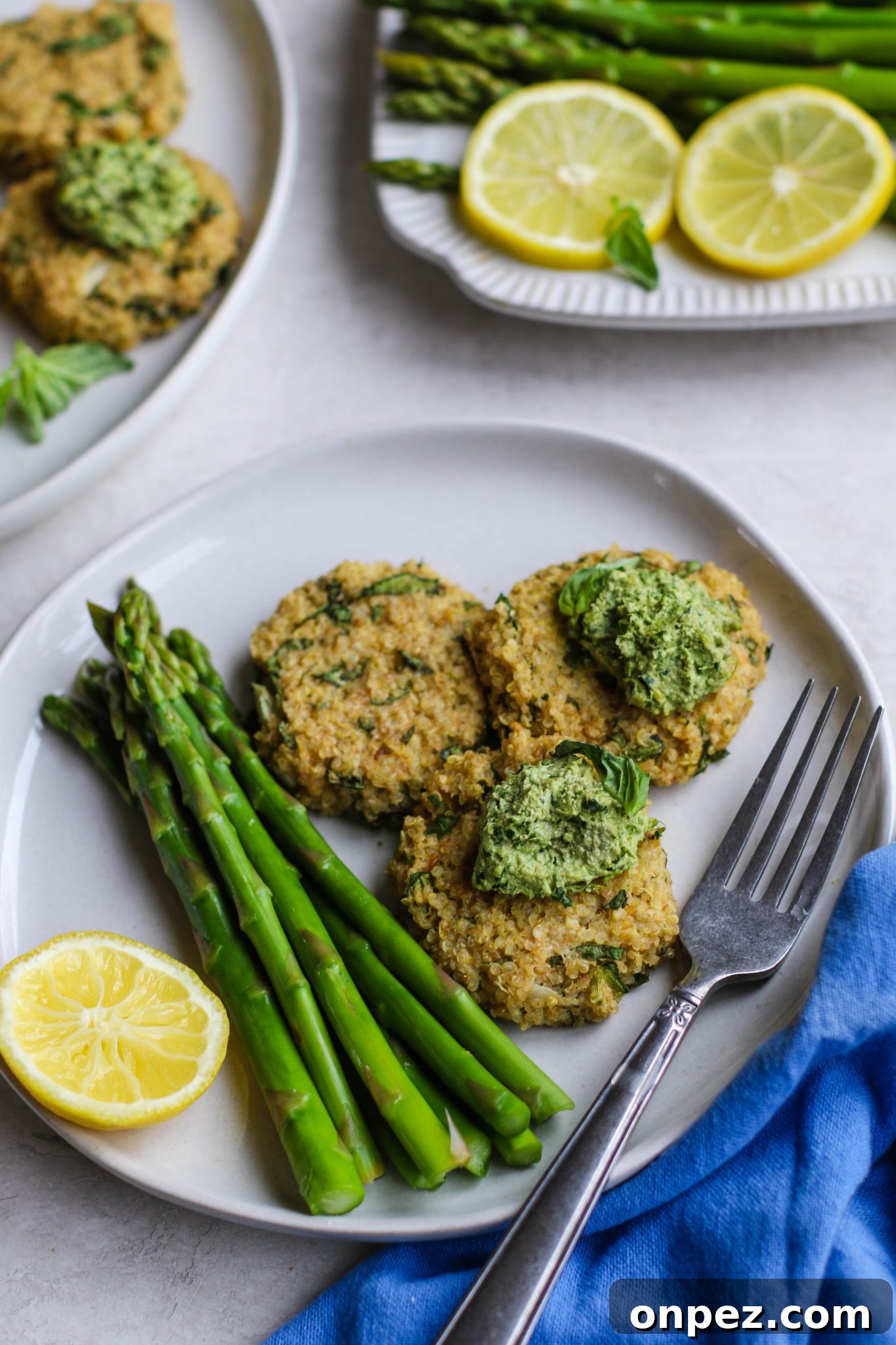 Quinoa Cakes with Basil Pesto served on plate with asparagus and a fork by Flora & Vino