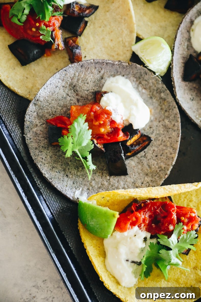 close up of eggplant tacos with tomatoes and burrata on a baking sheet