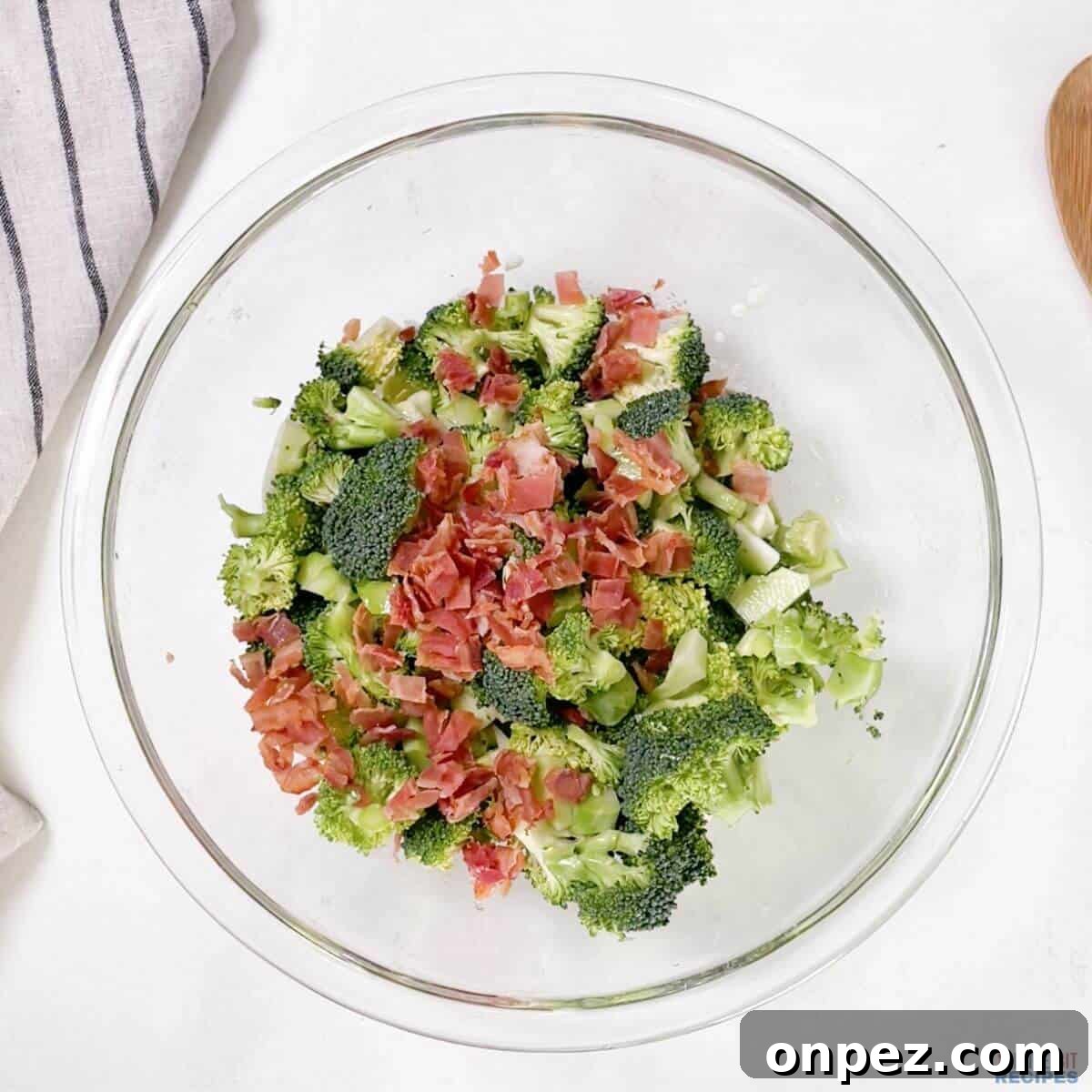 broccoli salad ingredients in glass mixing bowl.