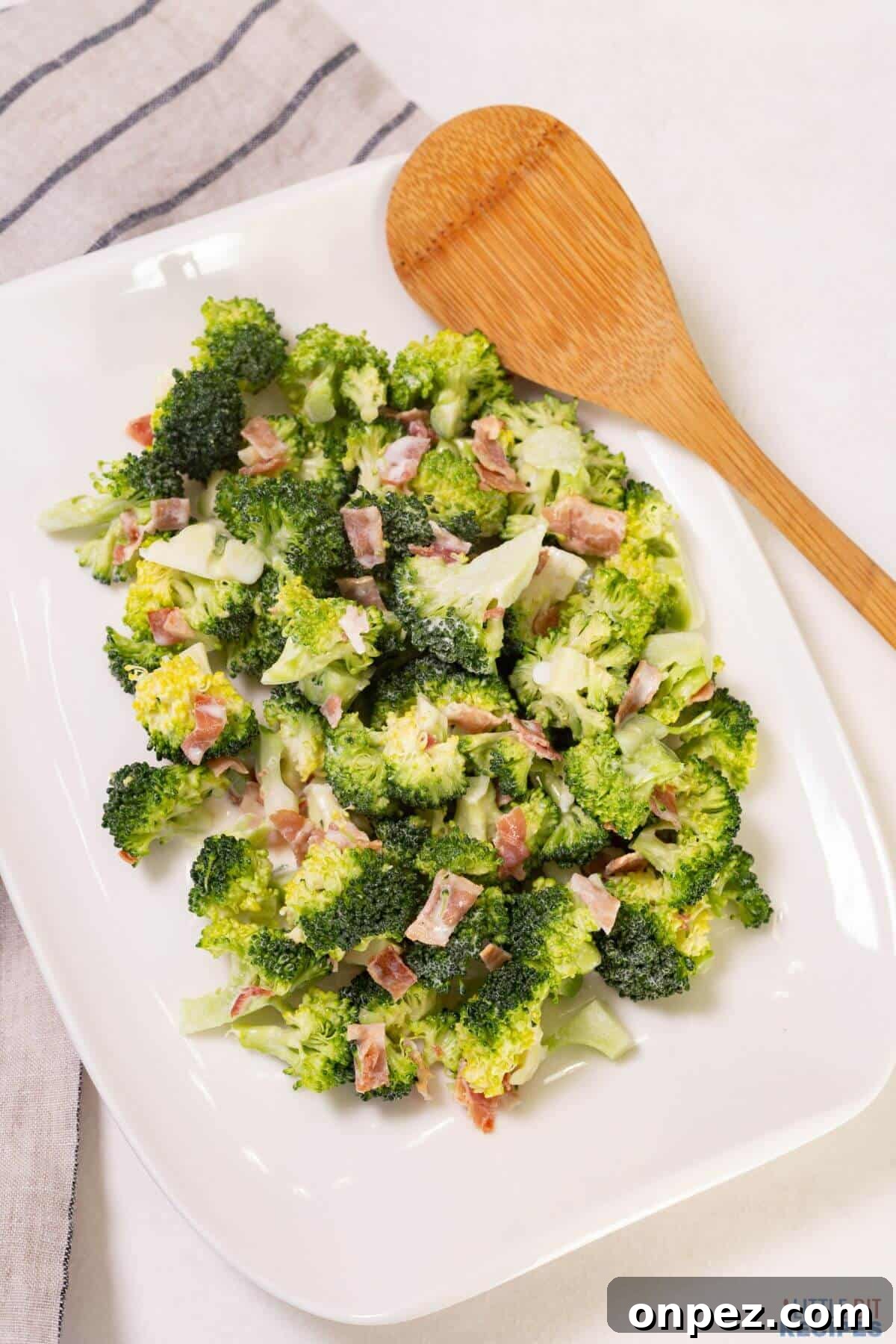 broccoli salad on platter with wooden spoon.