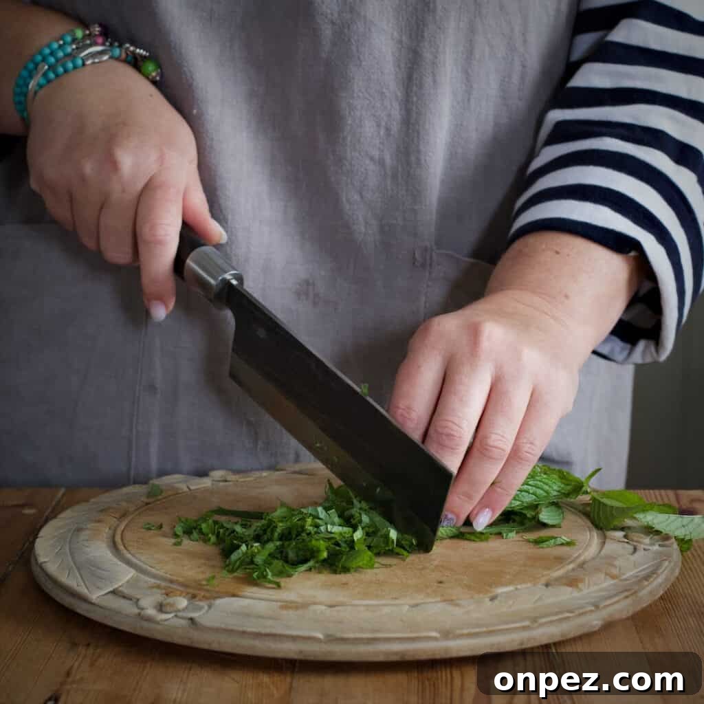 Homemade Mint Sauce Recipe for Lamb and Roasts 5 Woman finely chopping mint with a large Japanese knife on a rustic wooden board
