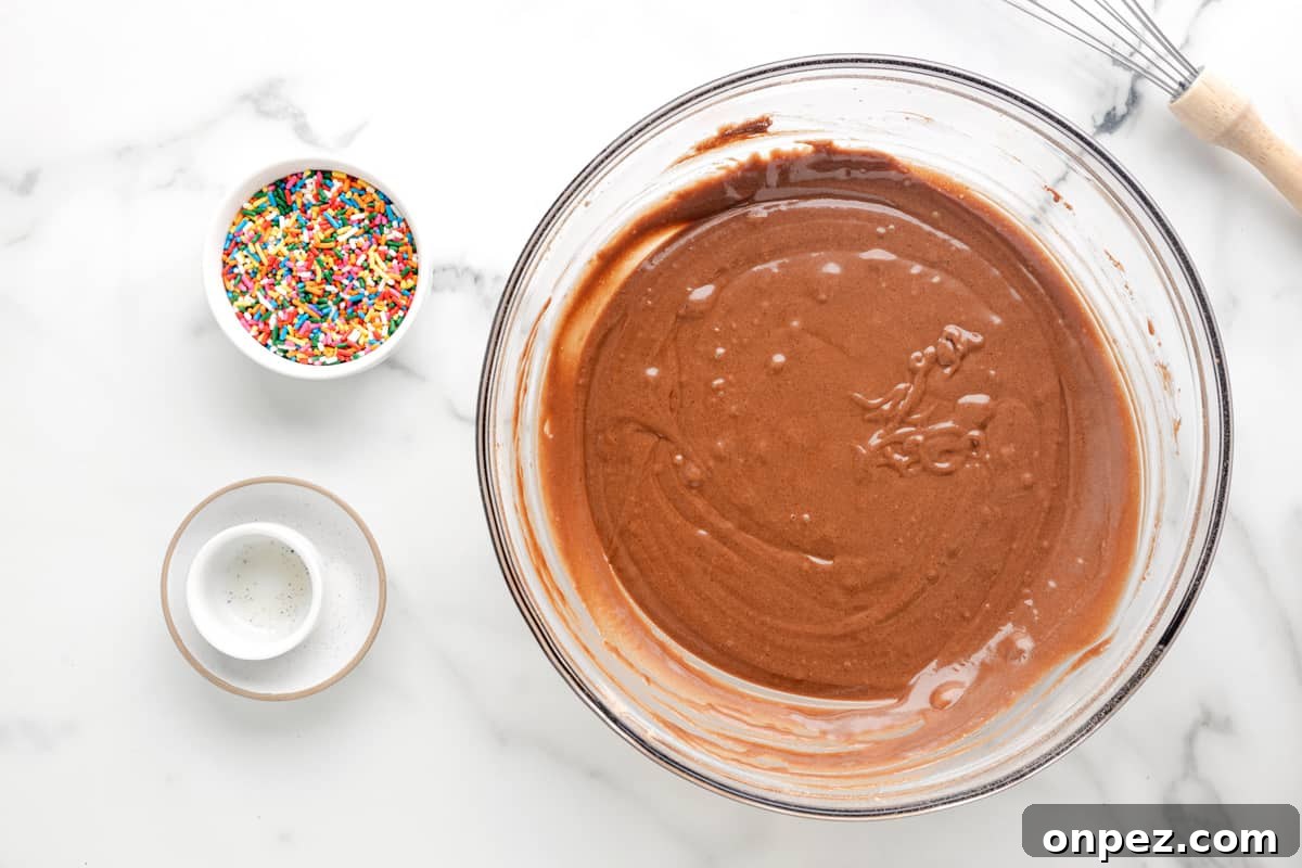 Classic Depression-Era Chocolate Cake (No Eggs, No Milk) 5 a bowl of chocolate ganache with sprinkles and a whisk.