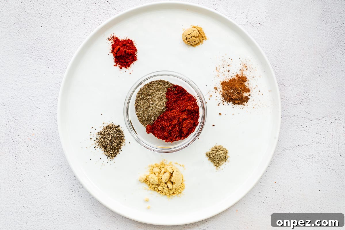 Ground ingredients for an easy Old Bay substitute are arranged on a white plate and placed on a concrete surface.