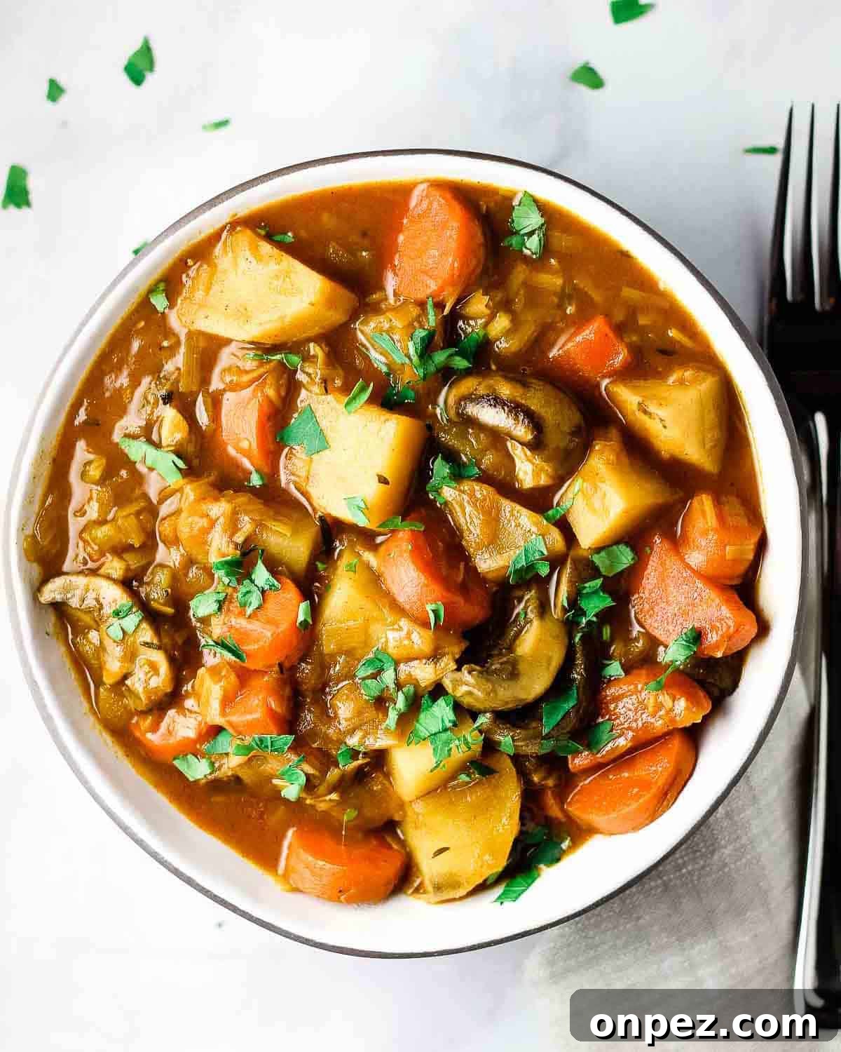 Overhead view of a bowl of vegan stew with a fork beside it.