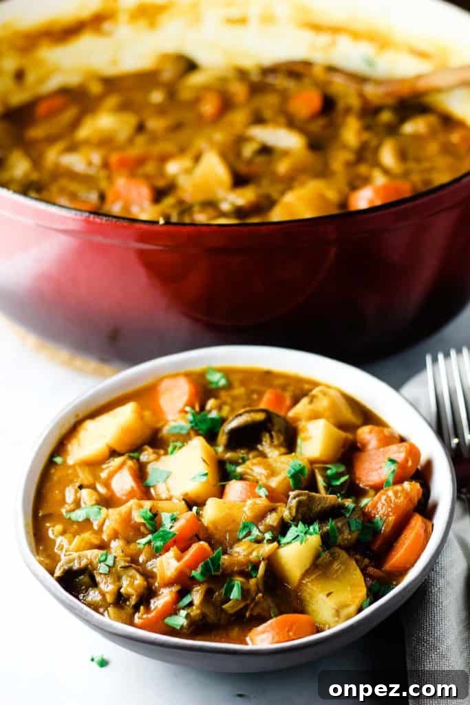 A bowl of vegan stew sprinkled with parsley, with the pot in the background