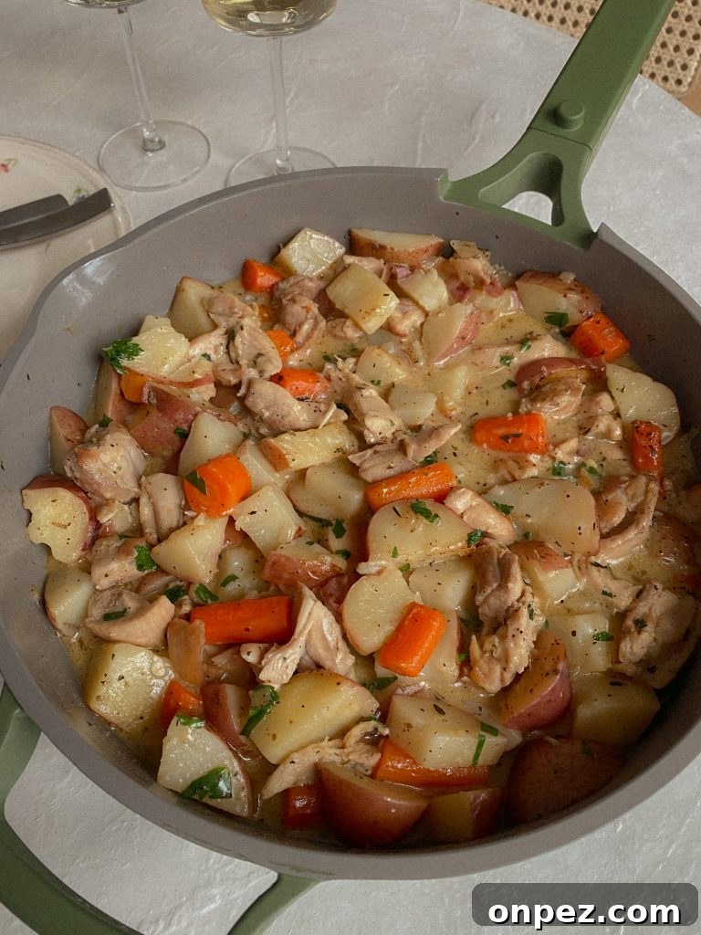 Chicken and Potato Skillet Recipe with carrots, herbs in a skillet on a table. 