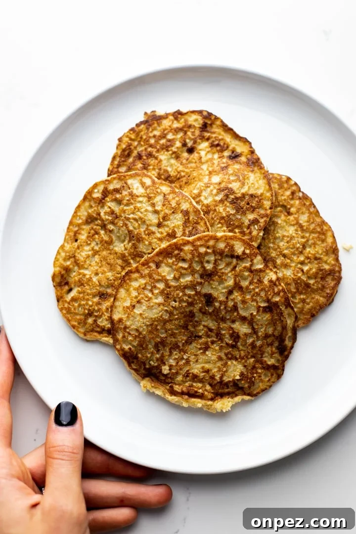 a hold holding a white plate with a stack of oatmeal banana pancakes.