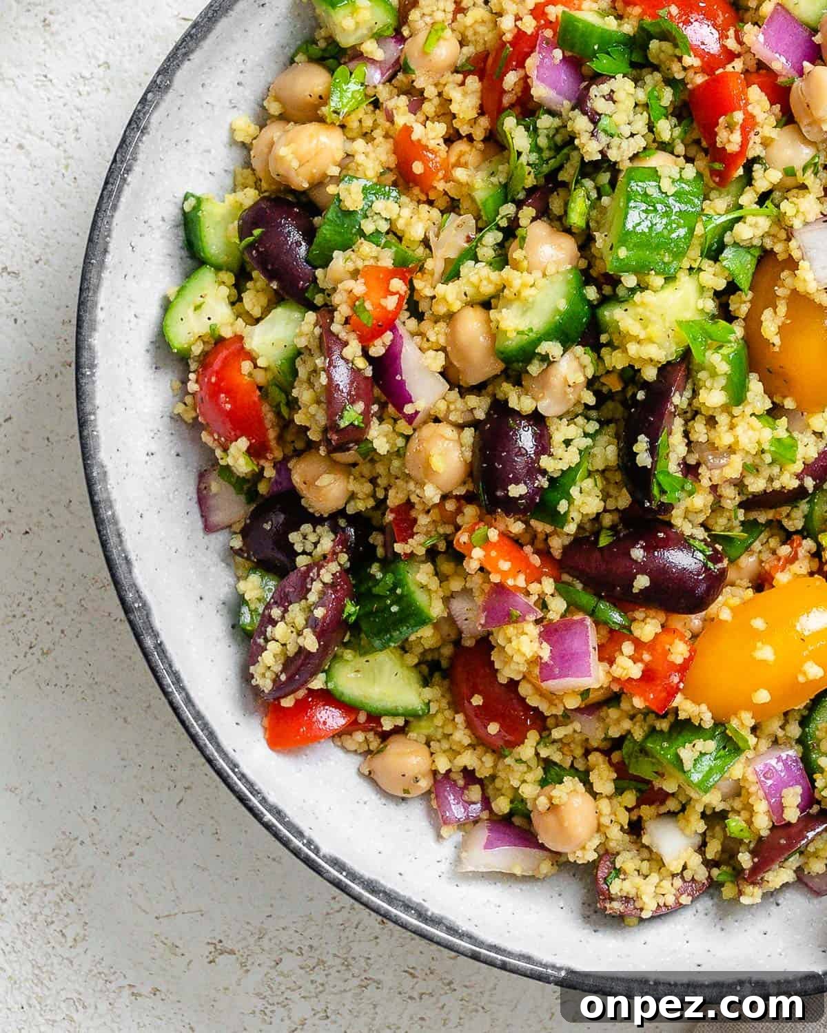 completed Mediterranean Couscous Salad plated against a white surface