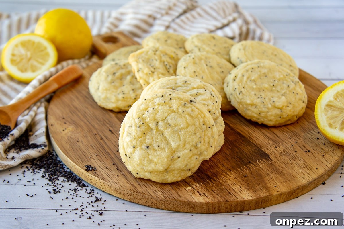 Lemon Poppy Seed Cookies with Bright Zesty Flavor 7 lemon poppy seed cookies displayed on a wooden board beside poppy seeds and a halved lemon.