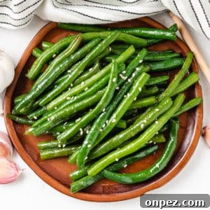Honey Garlic Glazed Green Beans 6 Top down view of Honey Garlic Green Beans on a wooden plate.