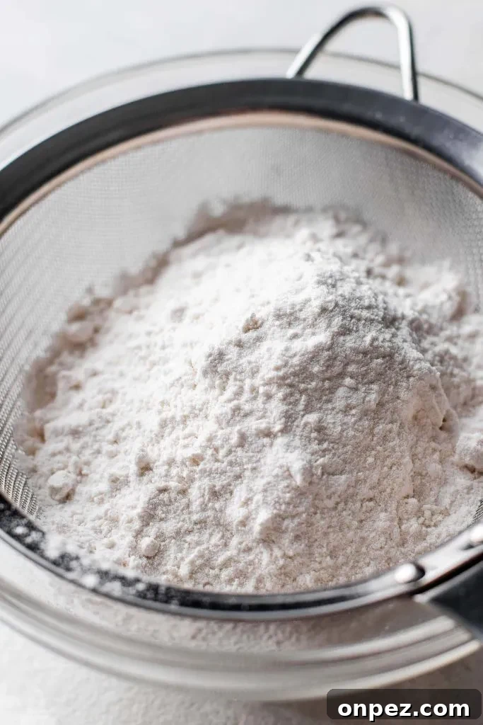 cake and pastry flour in mesh sifter set on top of parchment paper