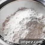 cake and pastry flour in mesh sifter set on top of parchment paper