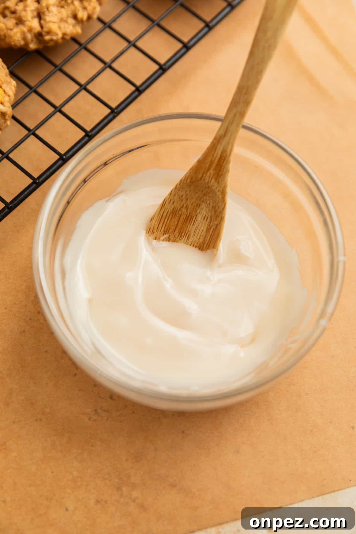 Icing glaze in bowl with wood spoon.