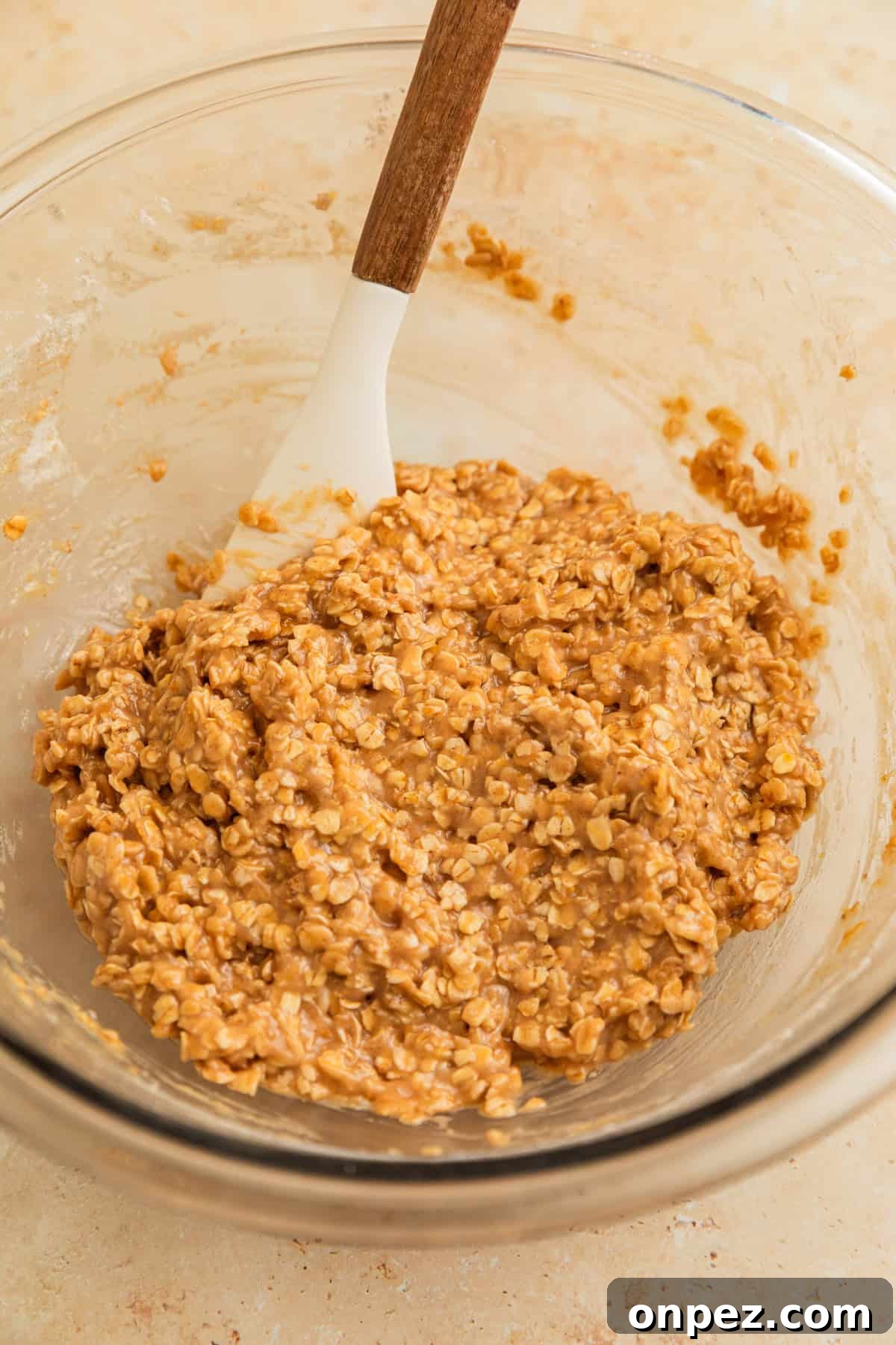 Cinnamon oatmeal cookie dough in bowl with spatula.