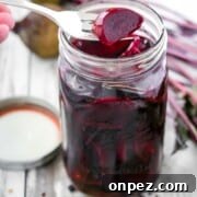 Pickled beets in a jar next to spices and beets.