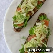 Open sandwiches topped with lettuce, salmon and fennel on a marble plate