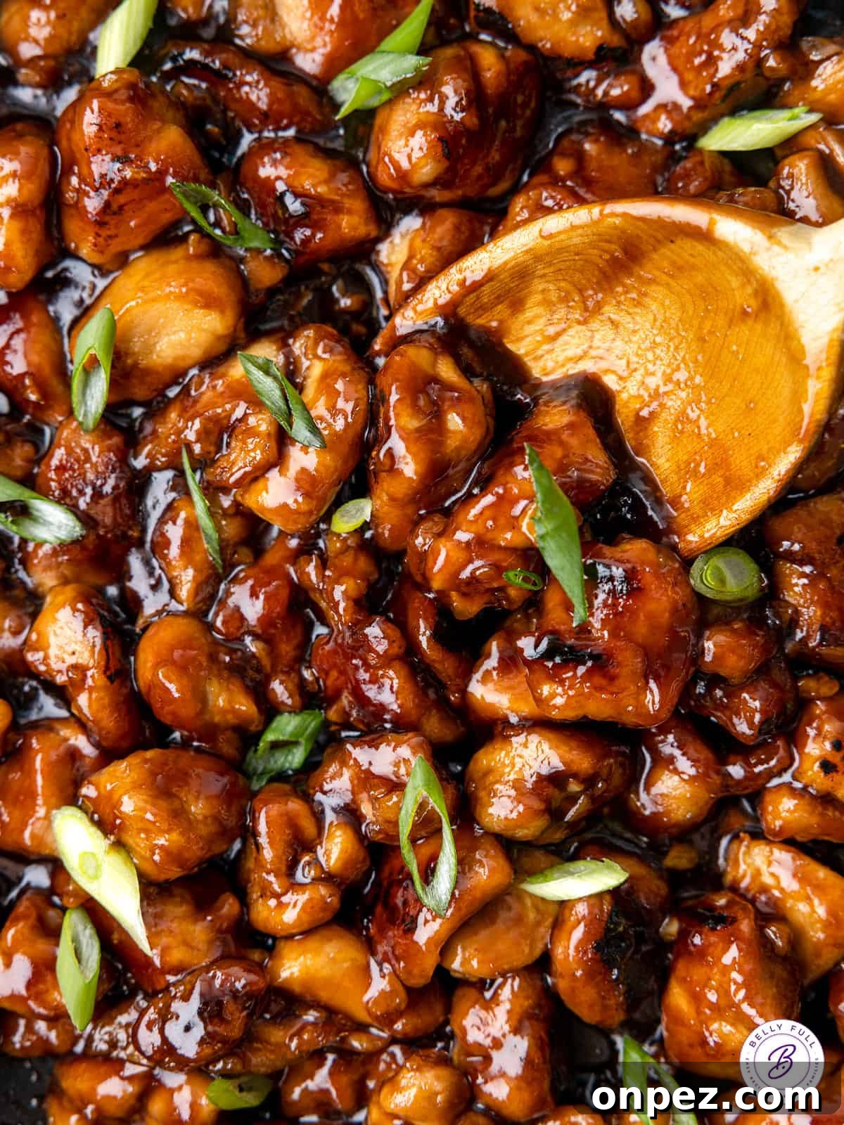 Featuring tender, juicy pieces of chicken in a sticky-sweet sauce, this Easy Bourbon Chicken tastes better than takeout! A wooden spoon stirring homemade bourbon chicken