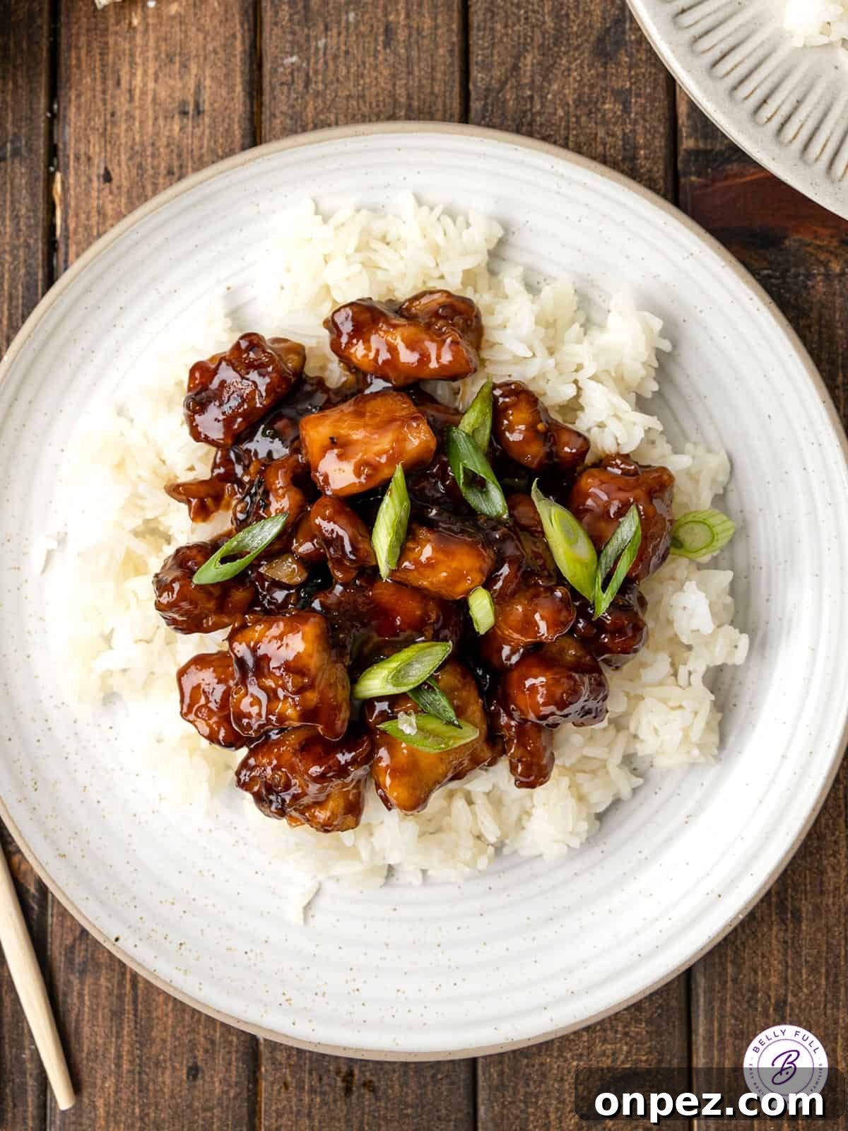 Featuring tender, juicy pieces of chicken in a sticky-sweet sauce, this Easy Bourbon Chicken tastes better than takeout! Overhead view of bourbon chicken on white rice
